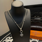 Silver-tone chain necklace on black bust with snowflake pendant and loop clasp