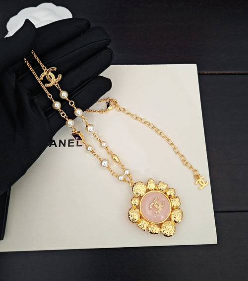 Gold-tone necklace with CC charm, pearl drops, and round pink pendant