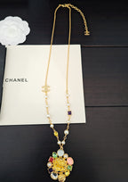 Gold-tone long pendant necklace with colorful bead accents and pearl details