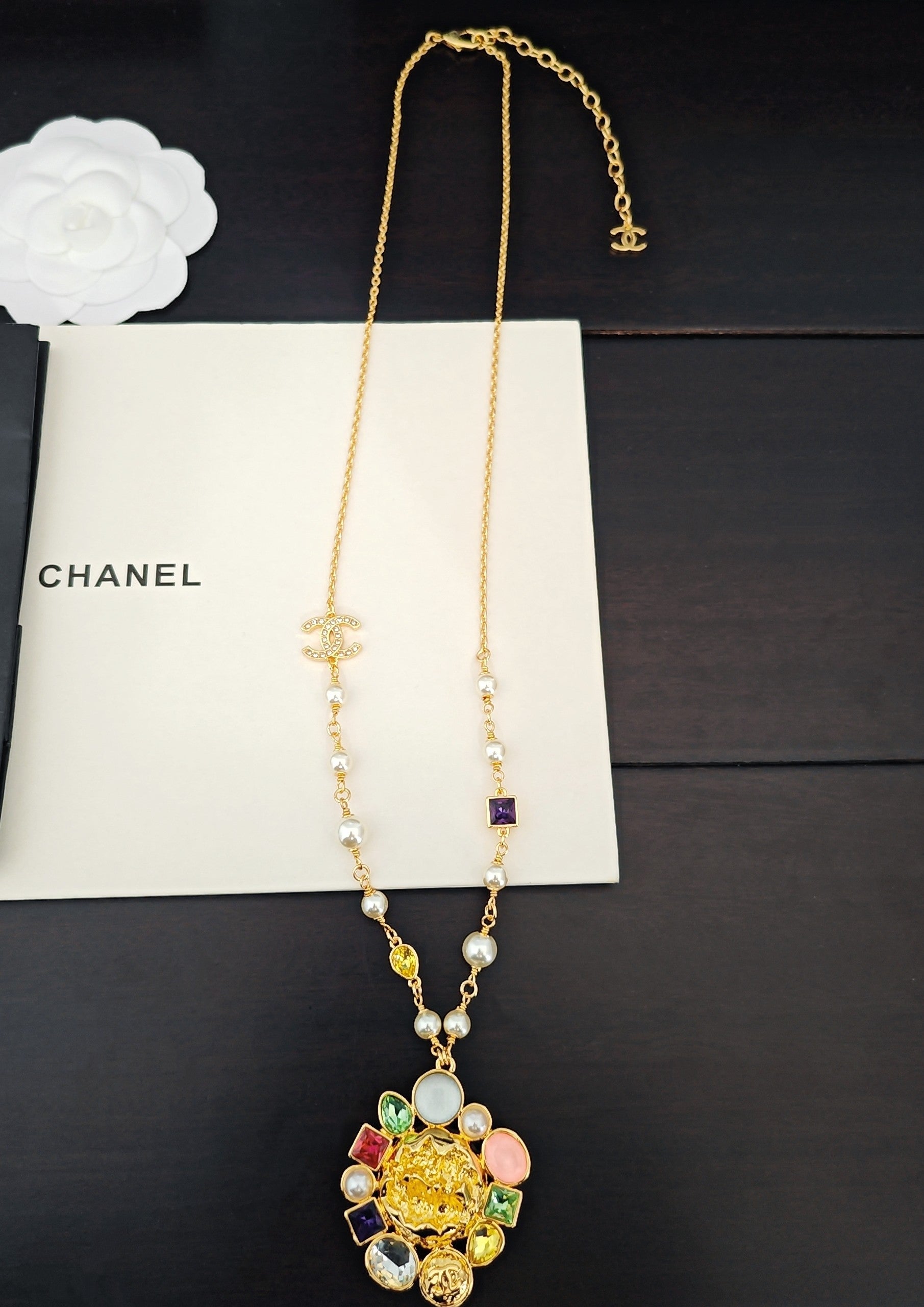 Gold-tone long pendant necklace with colorful bead accents and pearl details