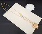 Gold-tone necklace with pearl strands, CC links, and round pink floral pendant