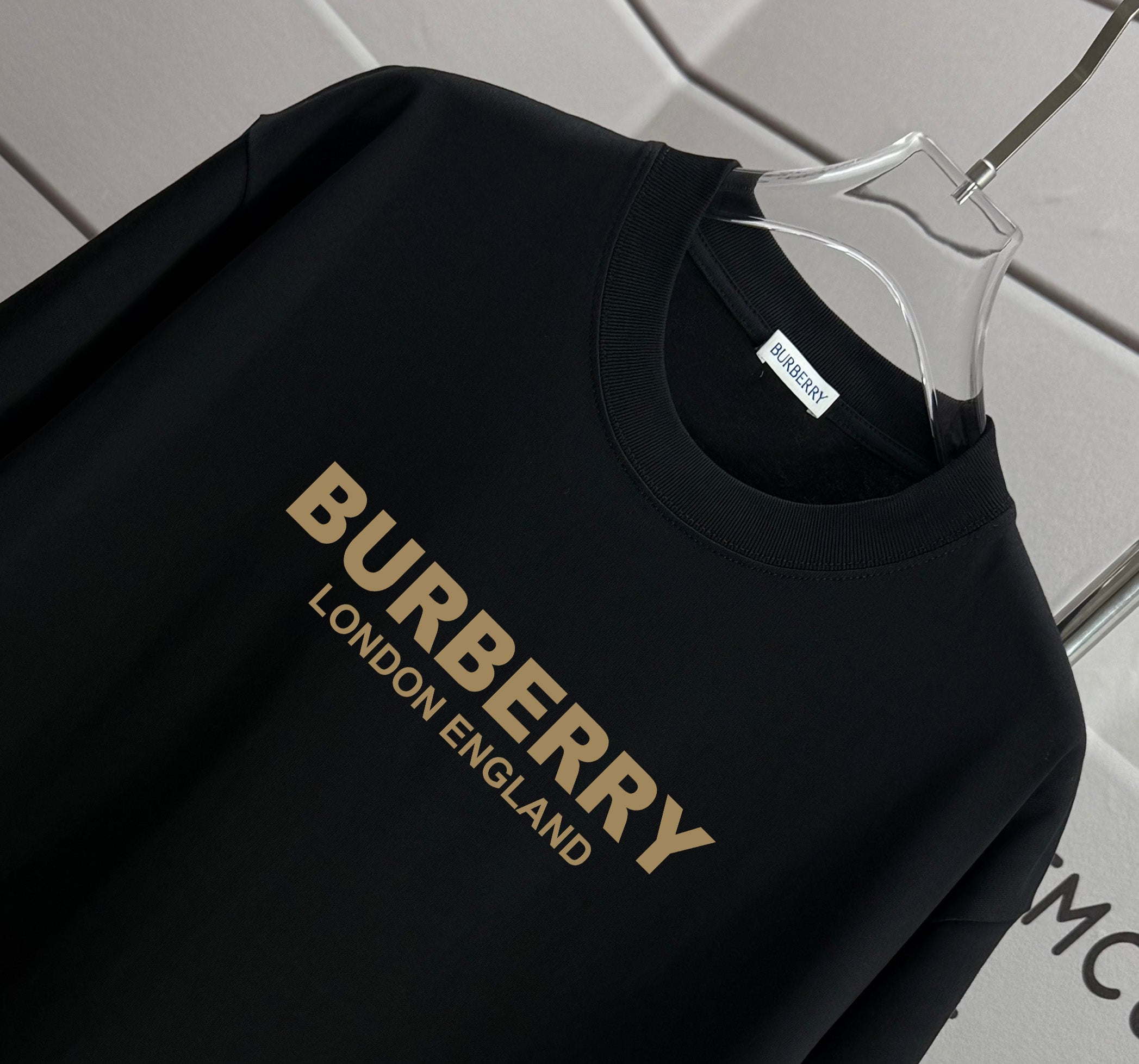 Burberry black T-shirt close-up with gold and gold “BURBERRY LONDON ENGLAND” text