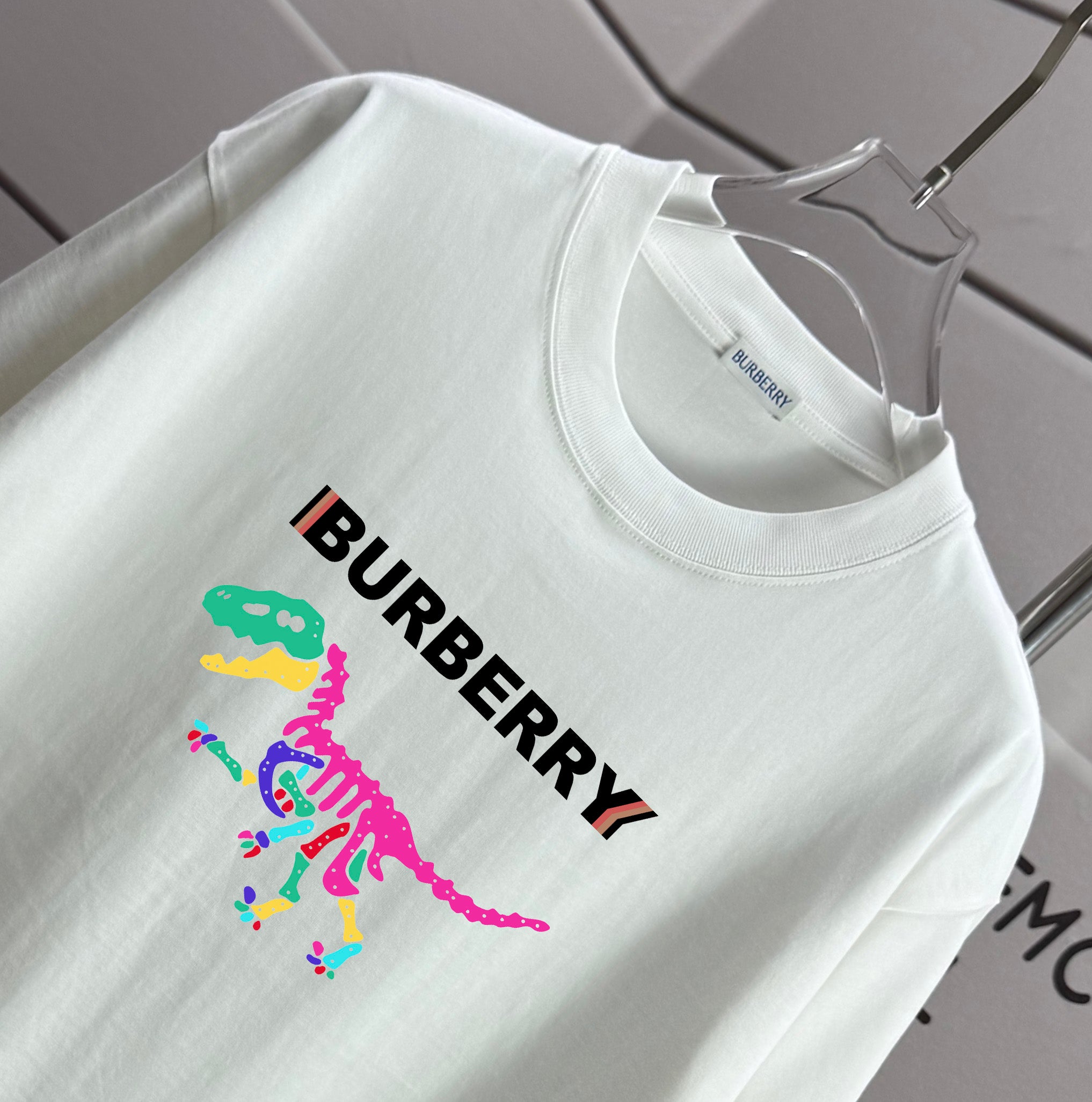 White short-sleeve T-shirt with Burberry text and multicolor dinosaur graphic
