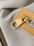 Louis Vuitton bag clasp detail: gold lock with yellow-stitched tan leather tab