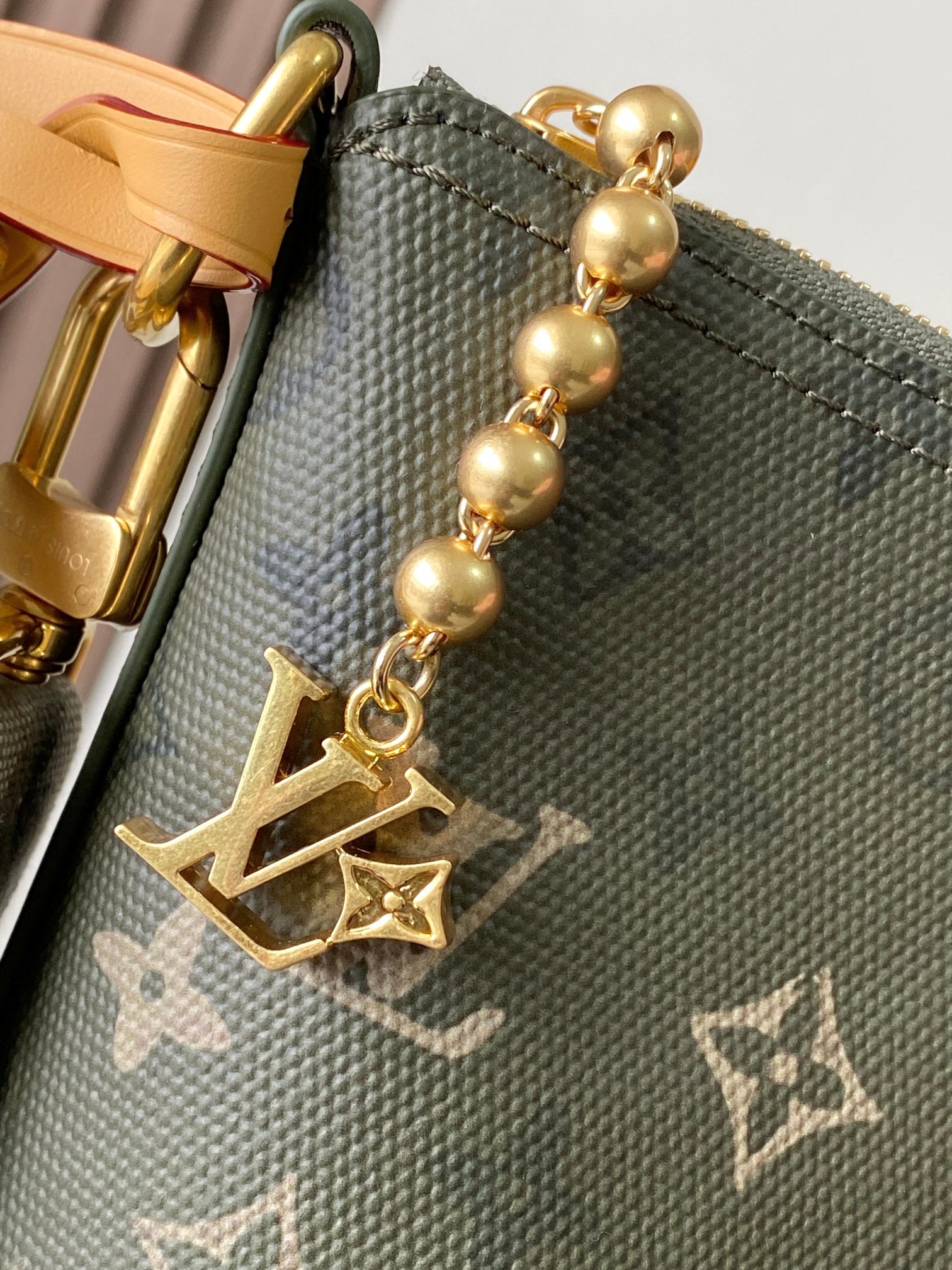 Monogram hobo bag charm detail with gold spheres and LV-style emblem