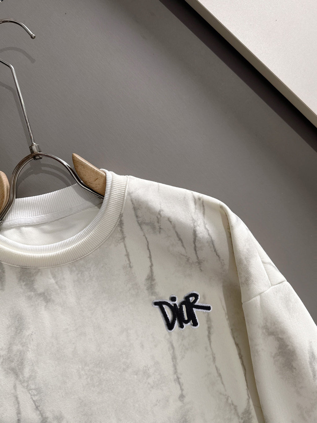 Crewneck sweatshirt close-up with black DiR logo and marbled light fabric