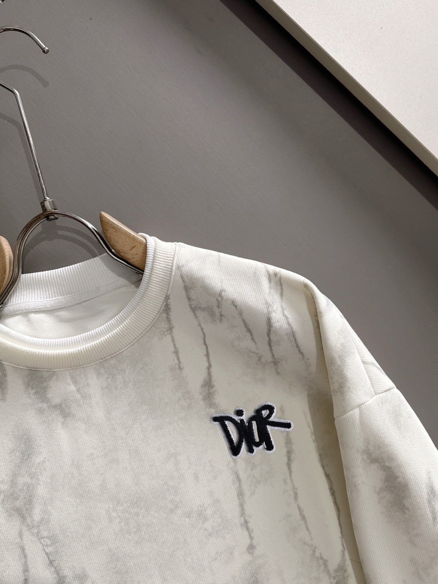 Crewneck sweatshirt close-up with black DiR logo and marbled light fabric
