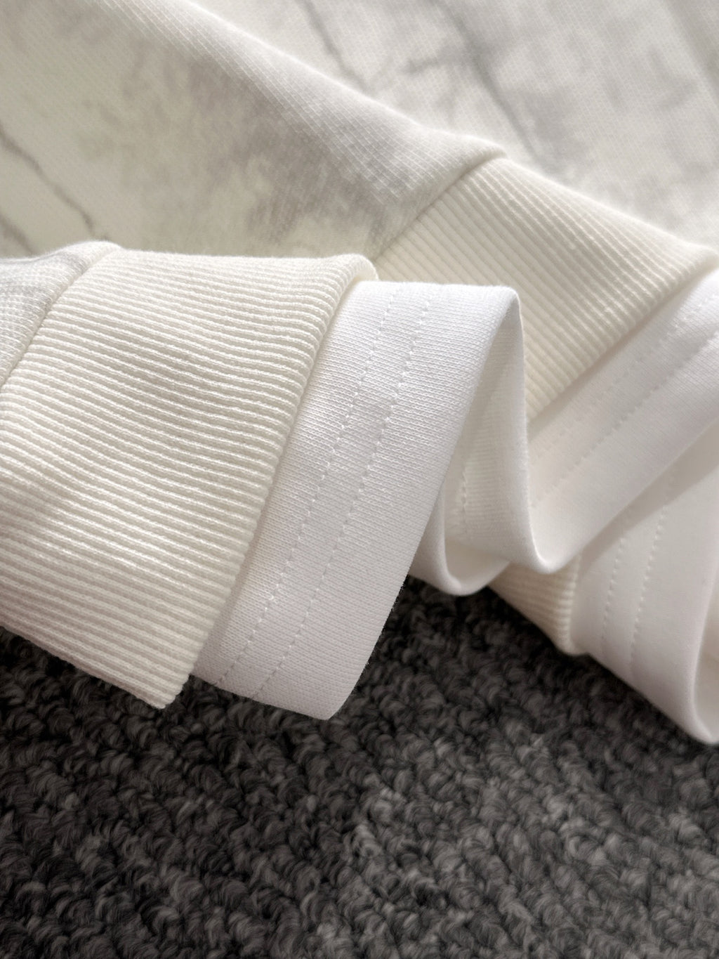 Ribbed knit cuffs and hem on marbled light sweatshirt sleeve