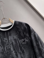 Black sweatshirt close-up: DiR logo with white-and-black ribbed crew collar