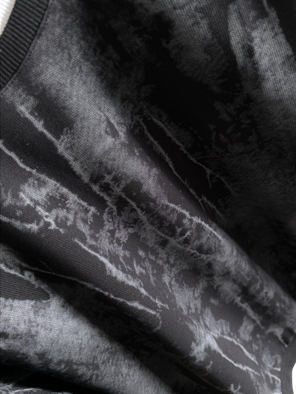 Black long-sleeve sweatshirt fabric close-up with light gray tie-dye streaks