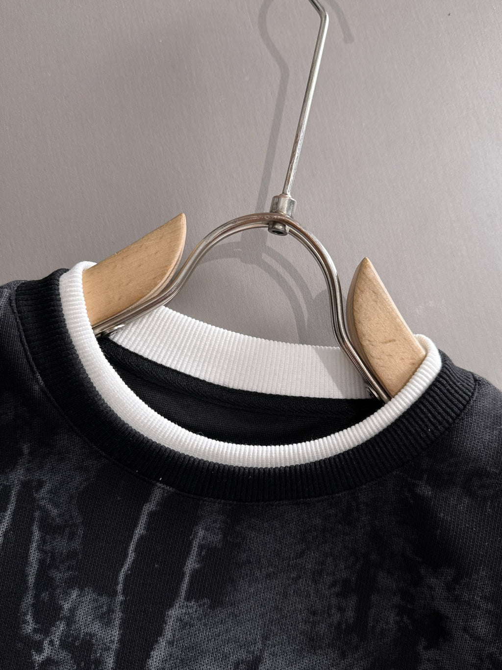 Black sweatshirt neckline close-up with white ribbed collar and hanger