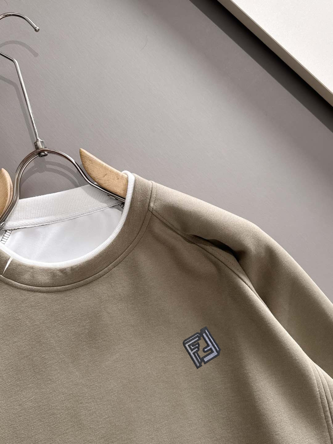 Beige crewneck sweatshirt neckline close-up with Fendi logo on chest