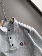 Light gray long-sleeve pullover with stand collar, black buttons, logo patch