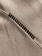 Cream fabric seam with zigzag black embroidery trim on a polo shirt