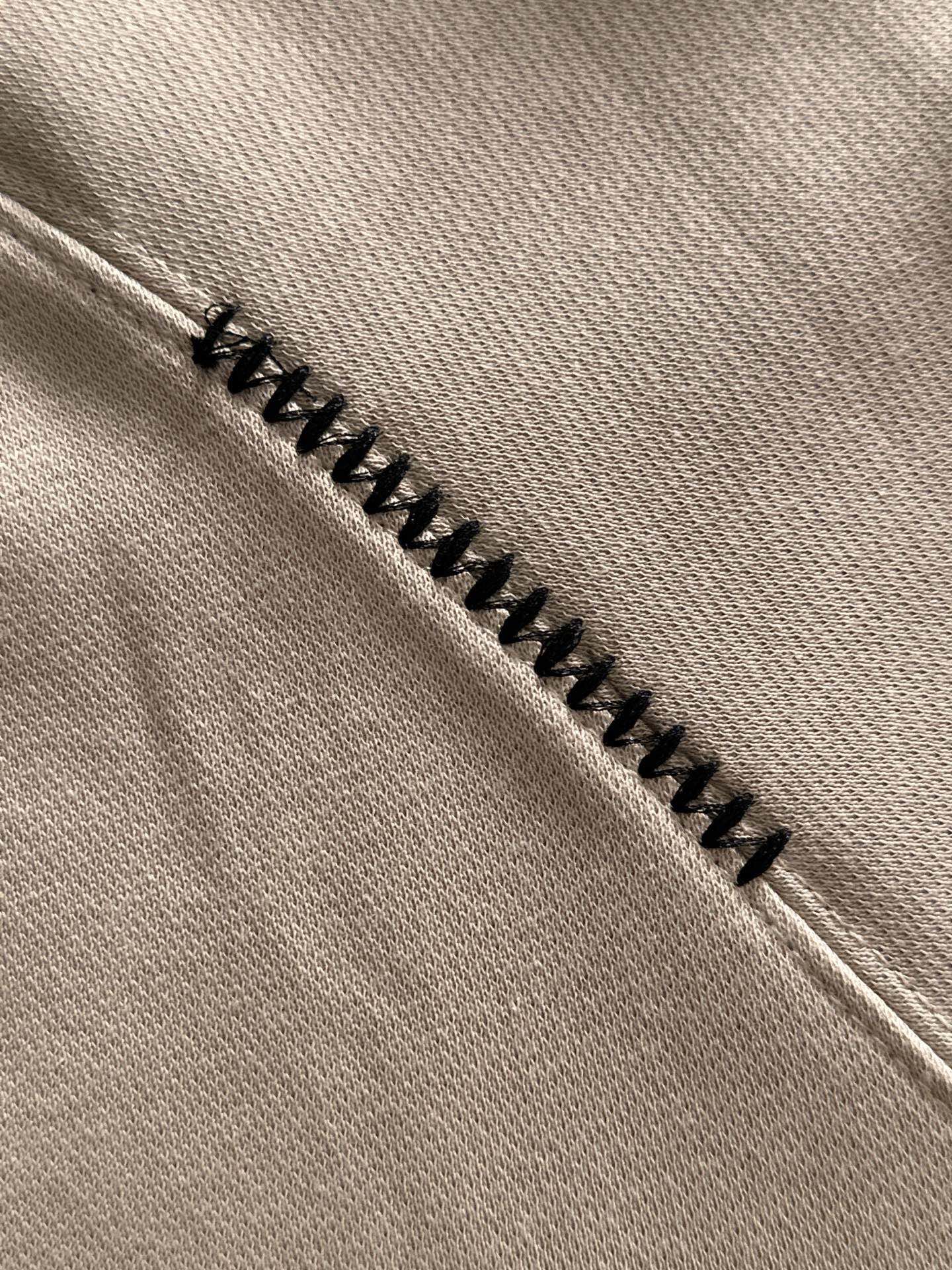Cream fabric seam with zigzag black embroidery trim on a polo shirt