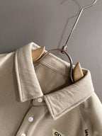 Cream polo shirt detail with point collar, white buttons, and interior neck label