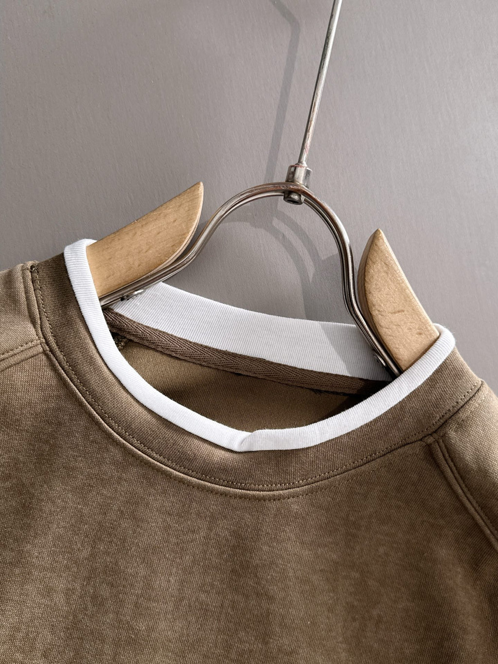 Gucci long-sleeve top neckline close-up on hanger, showing white inner trim