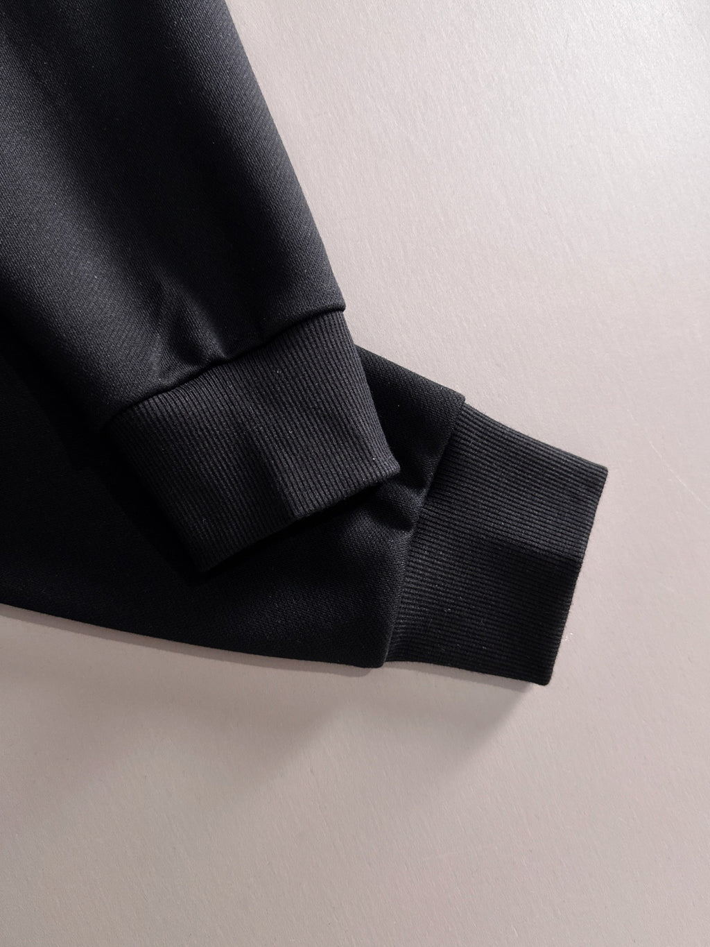 Black ribbed cuff and sleeve hem with white piping seam