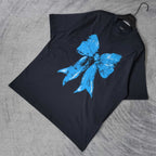 Balenciaga black T-shirt laid flat, blue bow graphic on front