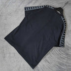 Balenciaga short-sleeve T-shirt flat lay, dark top with contrast striped sleeve trim