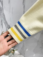 Cream knit sleeve cuff with ribbing and blue, gray, and yellow striped bands