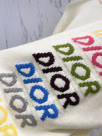 Cream knit sweater close-up of multicolor "DIOR" logo embroidery with scattered letters