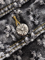 Denim jacket button detail with round engraved emblem and gold stitch accents