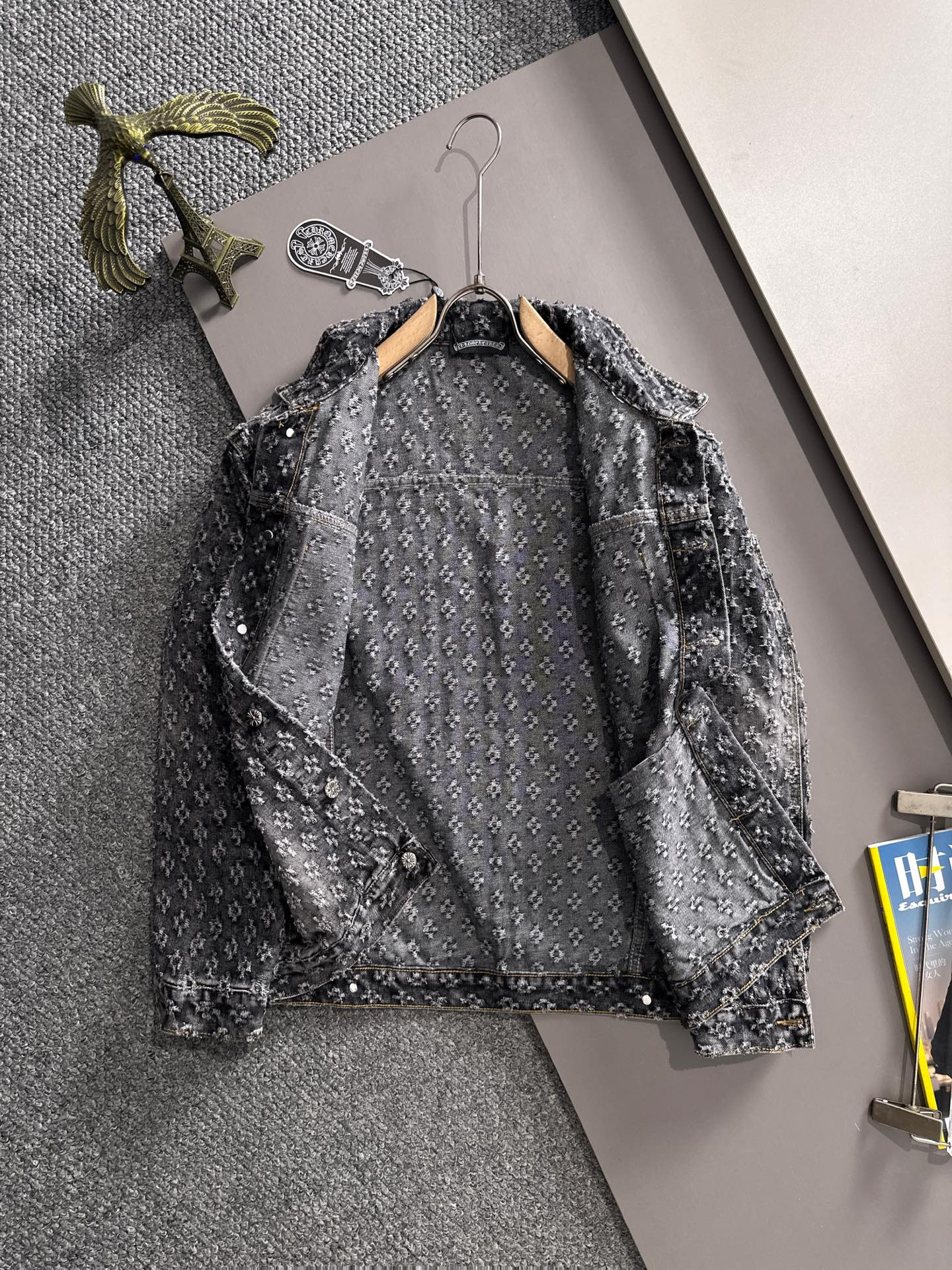 Distressed black denim jacket back view on hanger with button placket