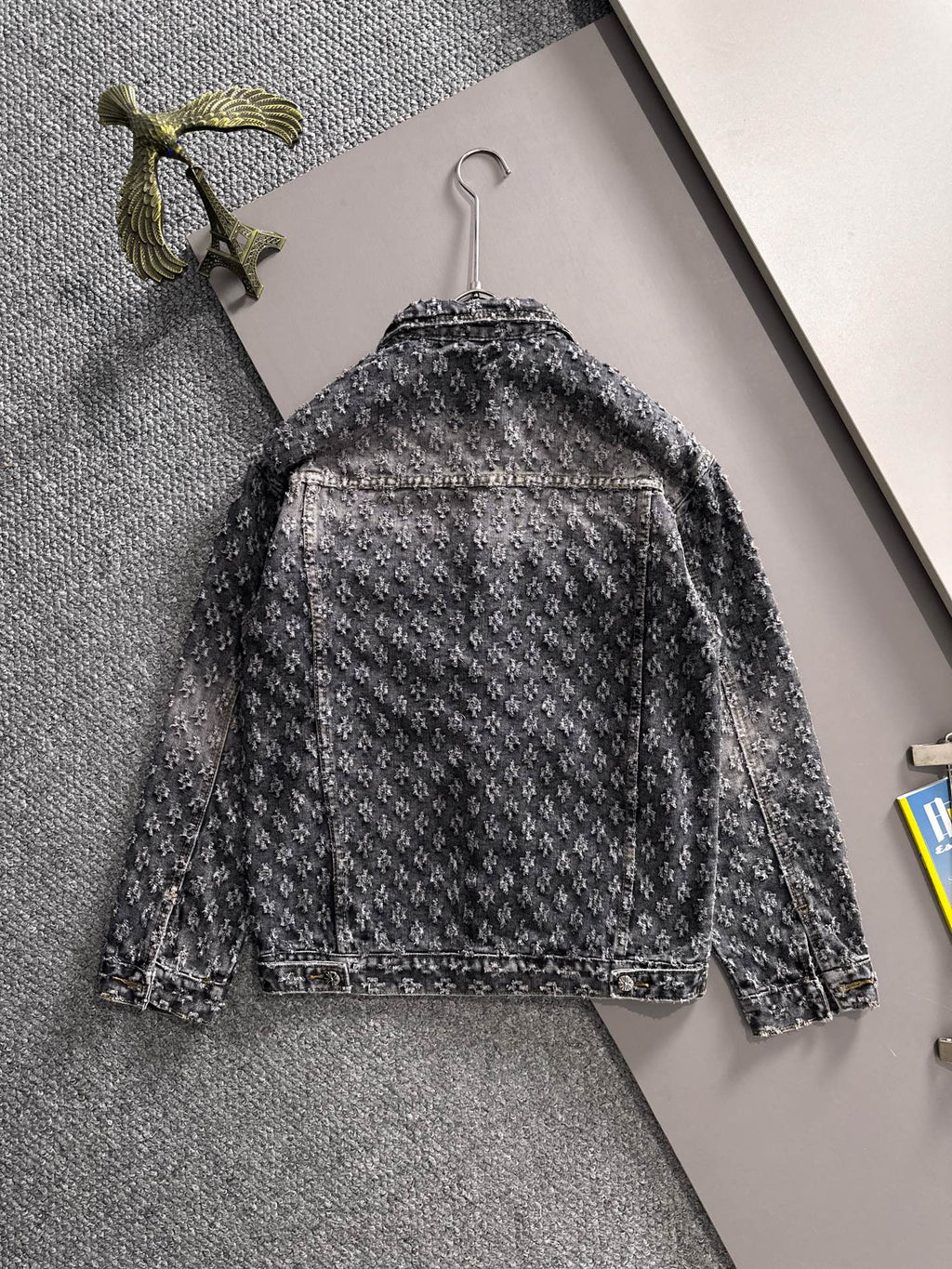 Distressed denim jacket back view on hanger with long sleeves and button placket