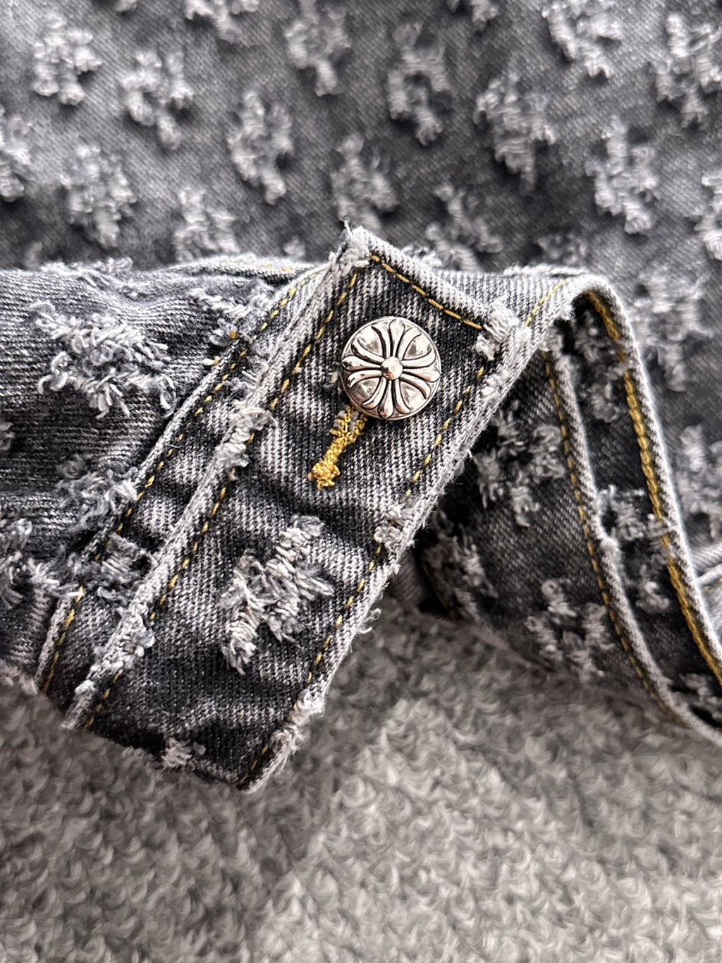 Denim jacket collar detail with round engraved button and gold cord trim