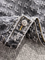 Denim jacket collar detail with round engraved button and gold cord trim