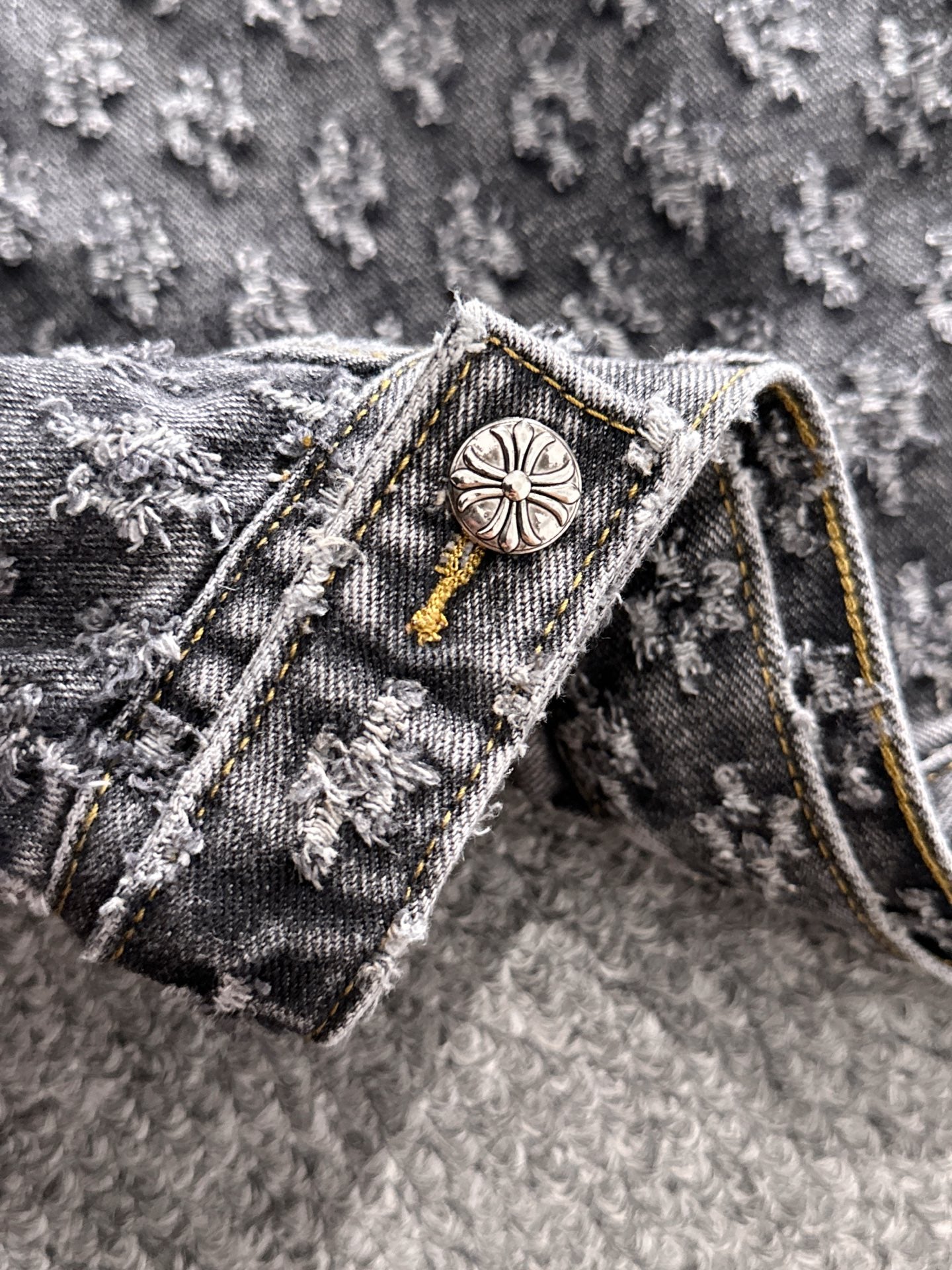 Denim jacket collar detail with round engraved button and gold cord trim
