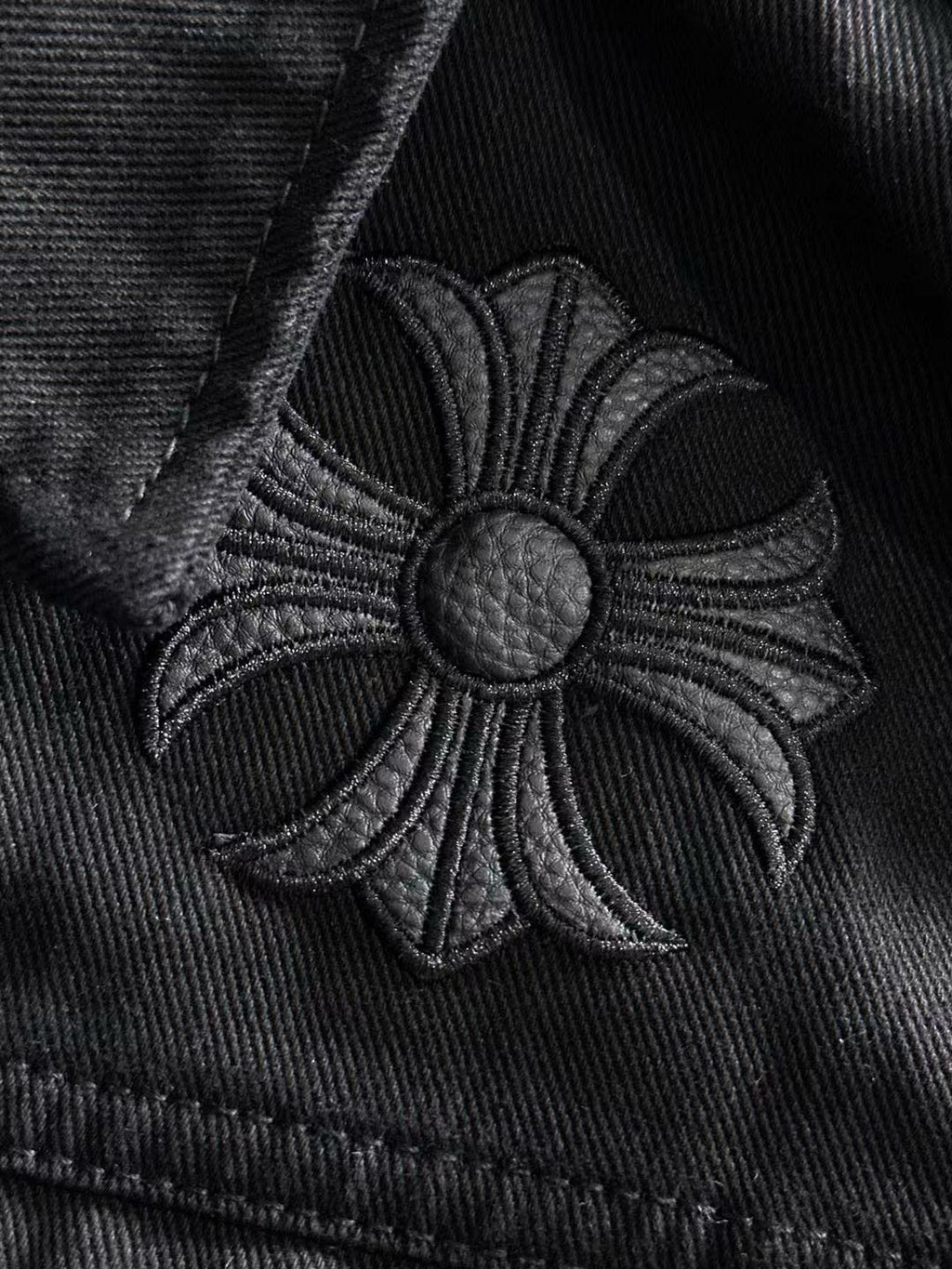Embroidered floral patch on black denim with round silver button center