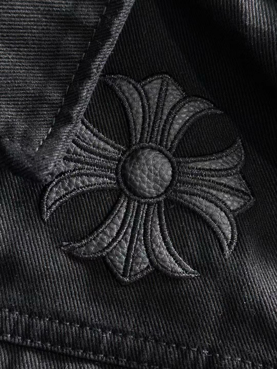 Embroidered floral patch on black denim with round silver button center