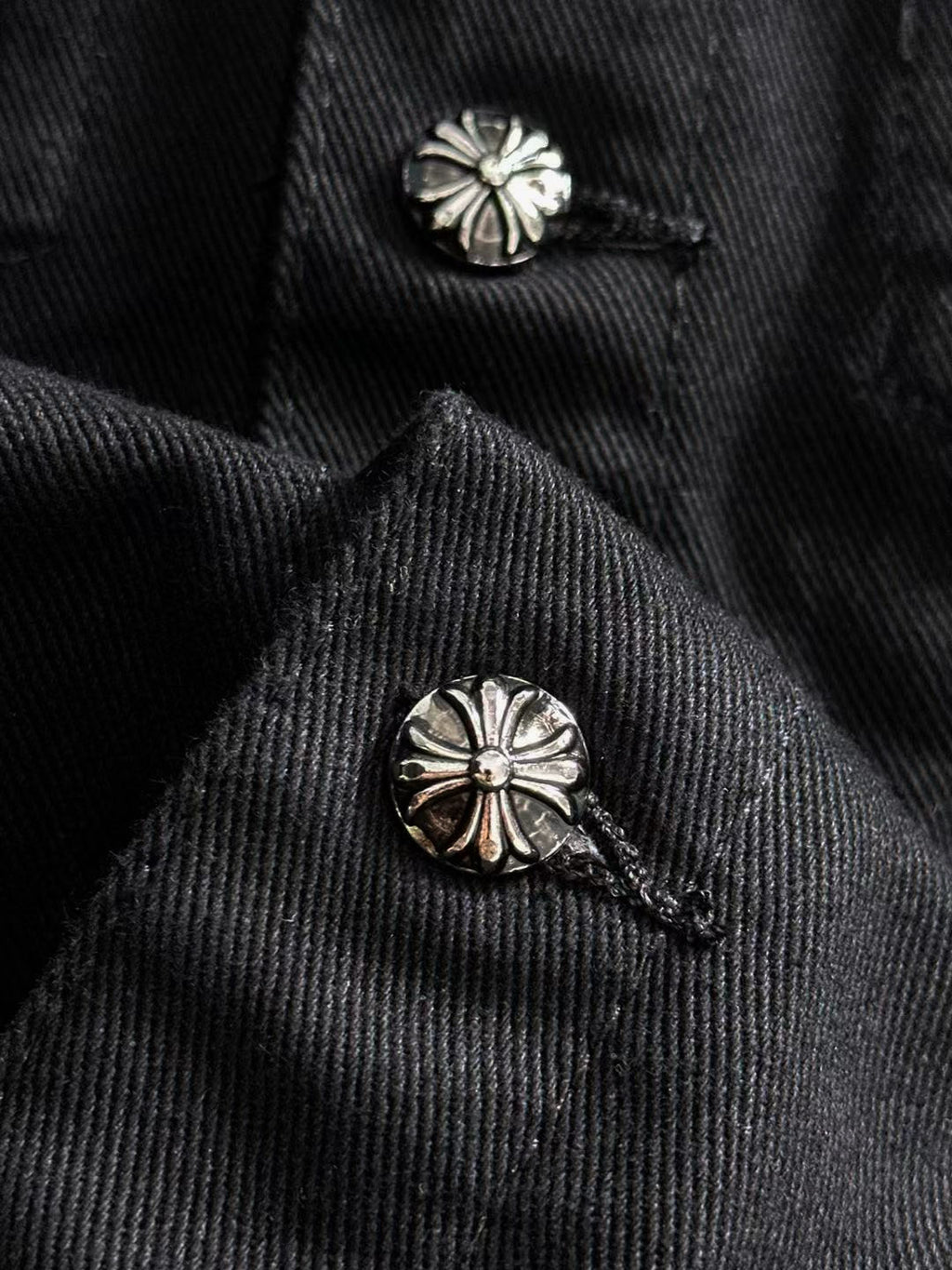 Black denim jacket collar with two silver floral stud buttons