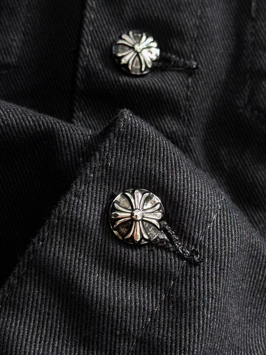 Black denim jacket collar with two silver floral stud buttons