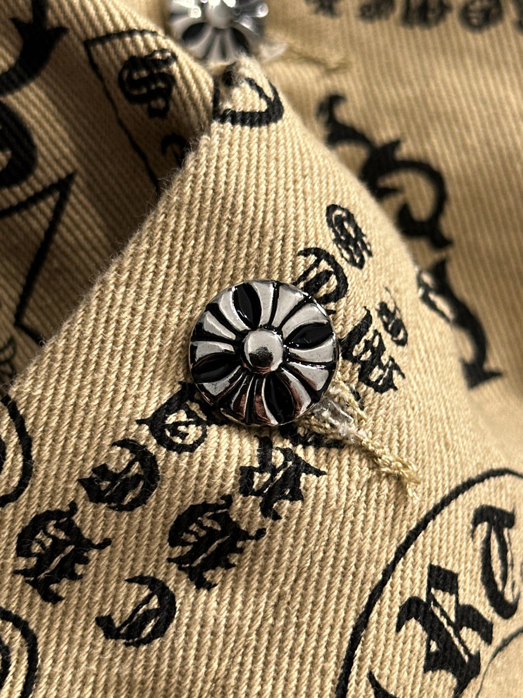 Long-sleeve shirt cuff with embroidered flower emblem on beige patterned fabric
