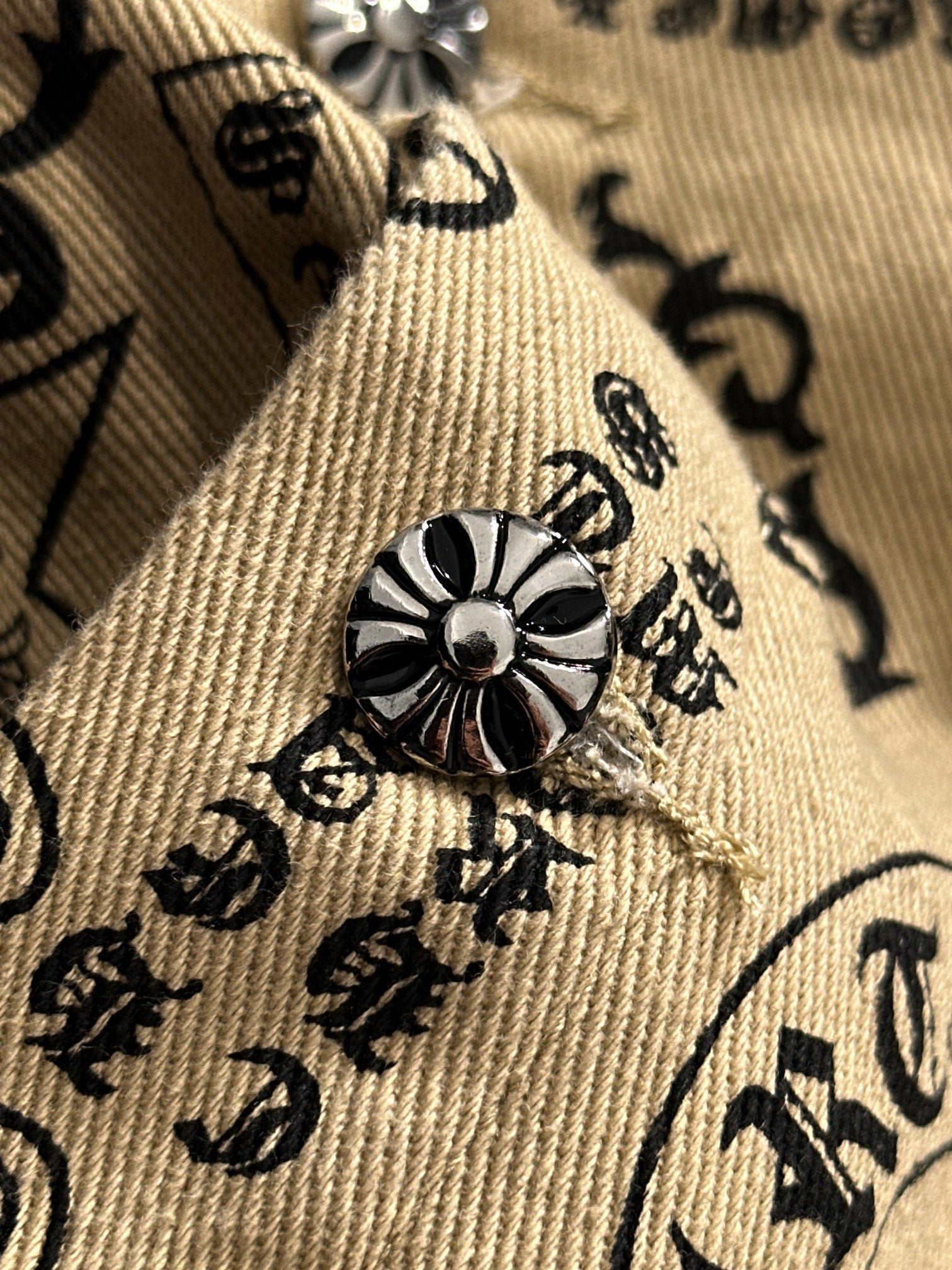 Long-sleeve shirt cuff with embroidered flower emblem on beige patterned fabric