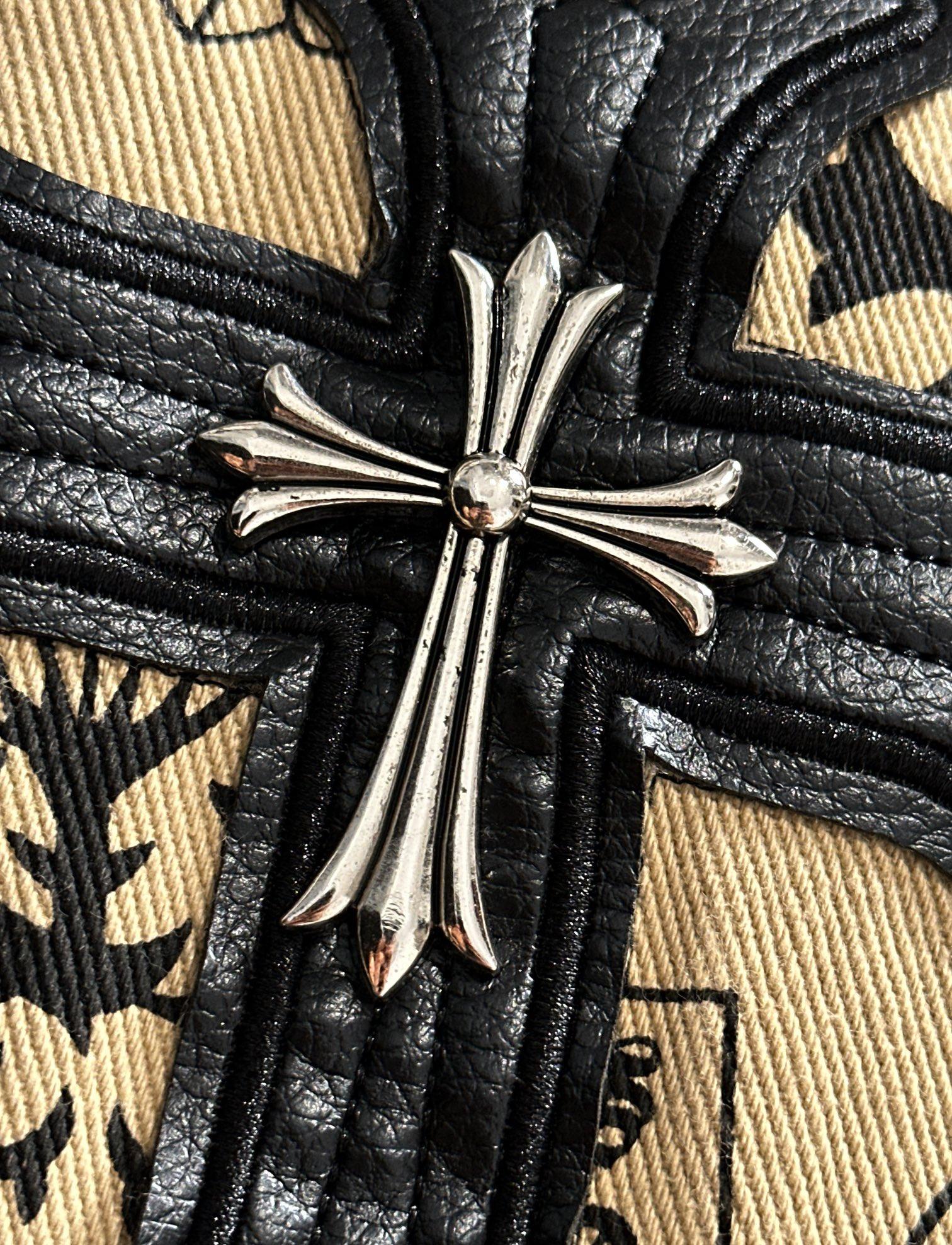 Long-sleeve shirt with black cross emblem on textured trim over beige fabric