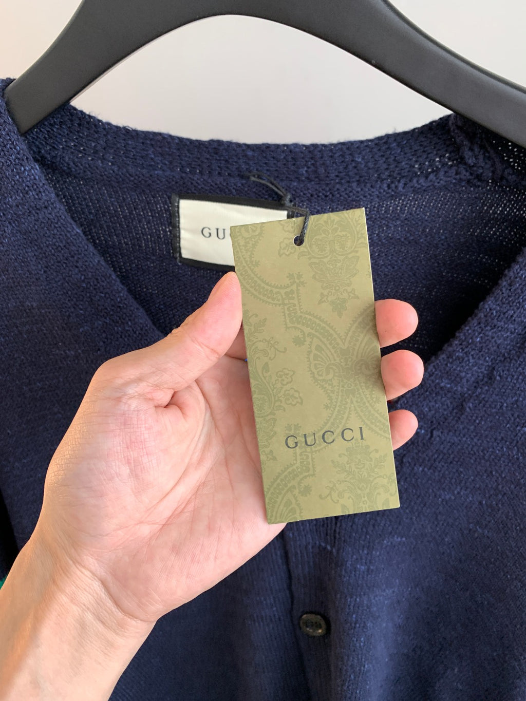 Gucci hang tag on navy knit cardigan at neckline