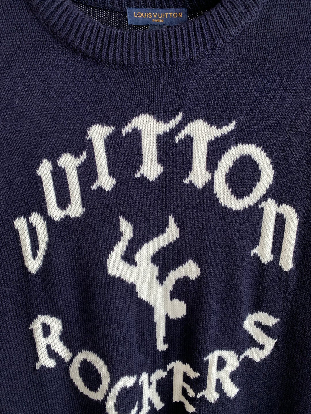 Navy knit sweater close-up of white lettering graphic and decorative marks