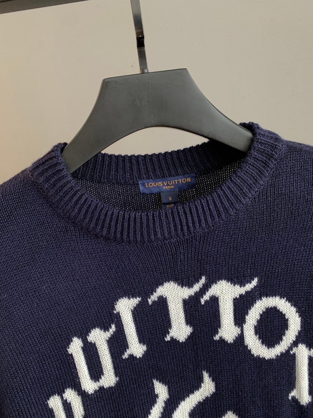 Navy crewneck sweater close-up with ribbed collar and white graphic logo