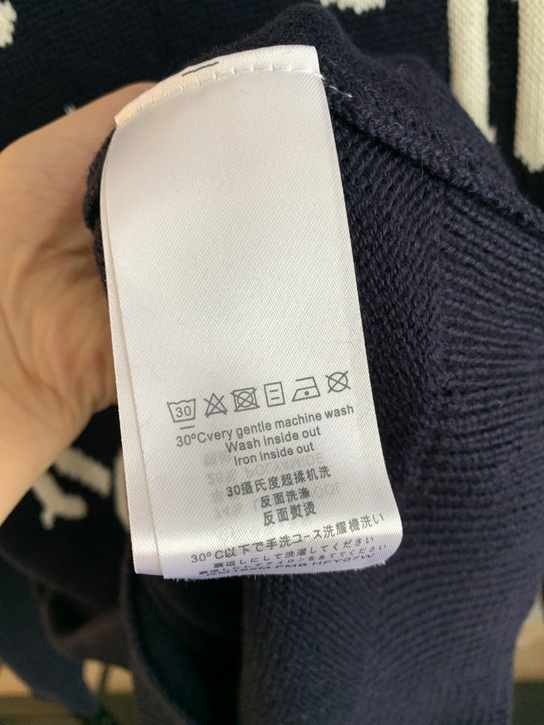 Navy knit sweater care label tag on inner collar area