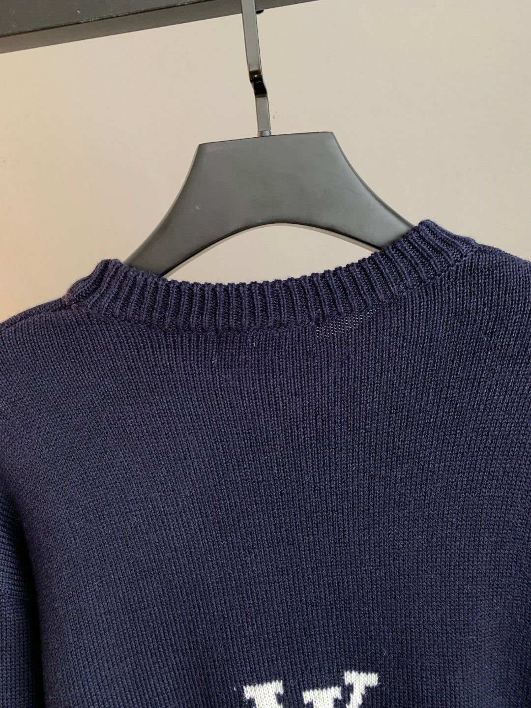 Navy crewneck sweater back close-up with ribbed collar and small white logo