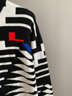 Knit sweater sleeve with black-and-white geometric stripes and red logo detail