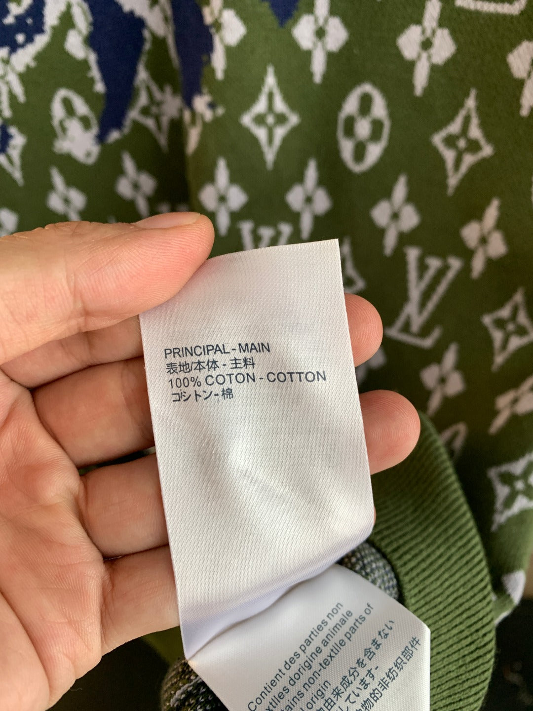 Louis Vuitton fabric composition tag showing 100% cotton on green knit sweater