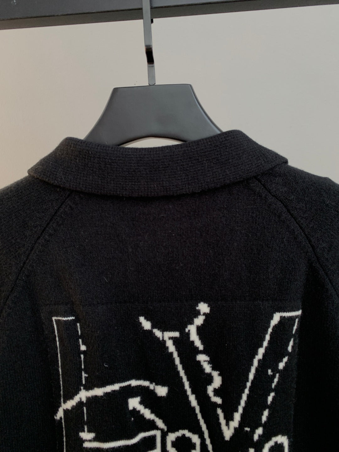 Dark knit cardigan back neckline and partial white graphic lettering