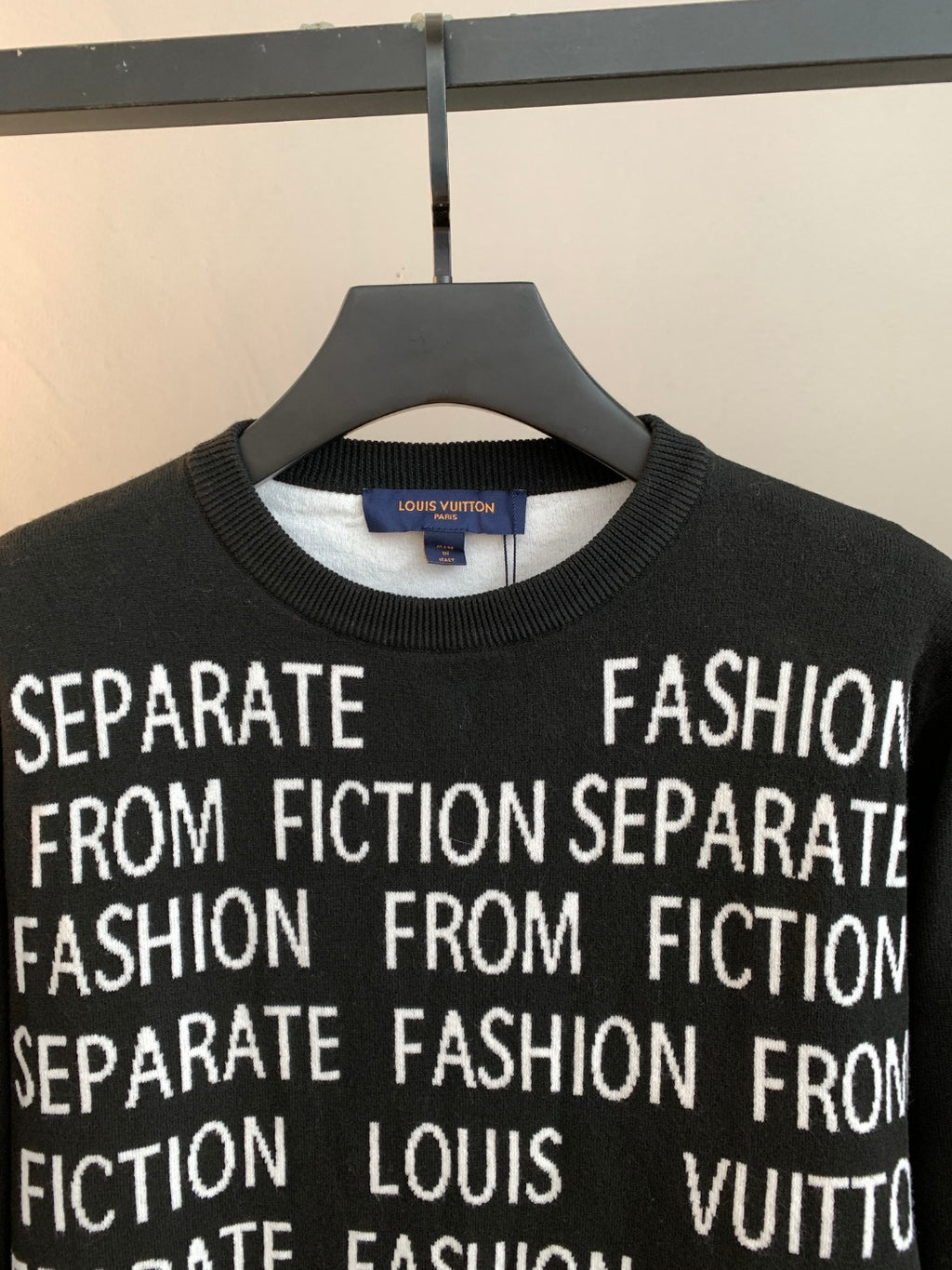 Black long-sleeve crewneck sweater with repeating white "Fashion" and "Fiction" text
