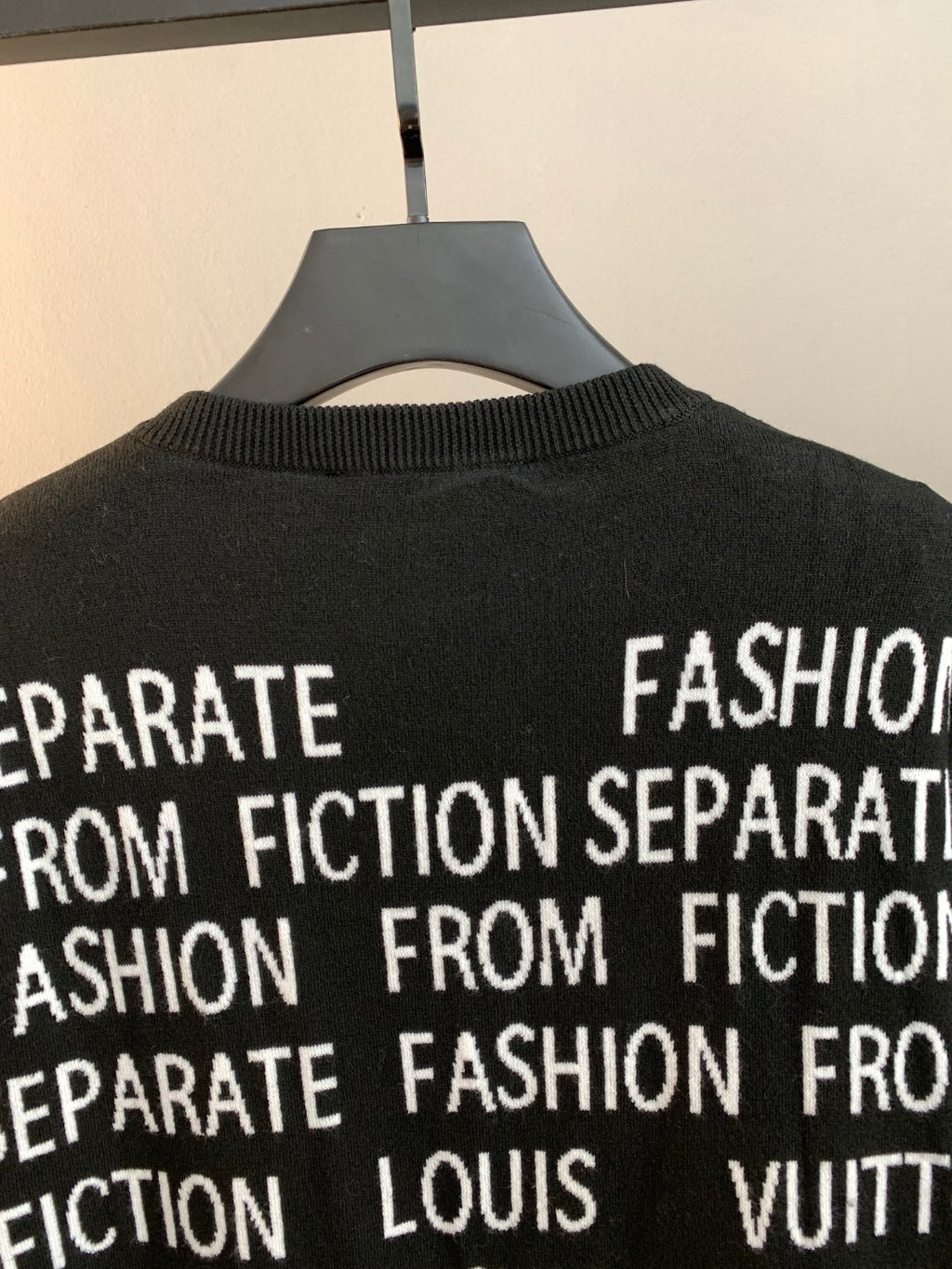 Black crewneck sweater with white text print near collar and upper chest
