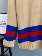 Cream knit sweater hem with red and blue stripe band